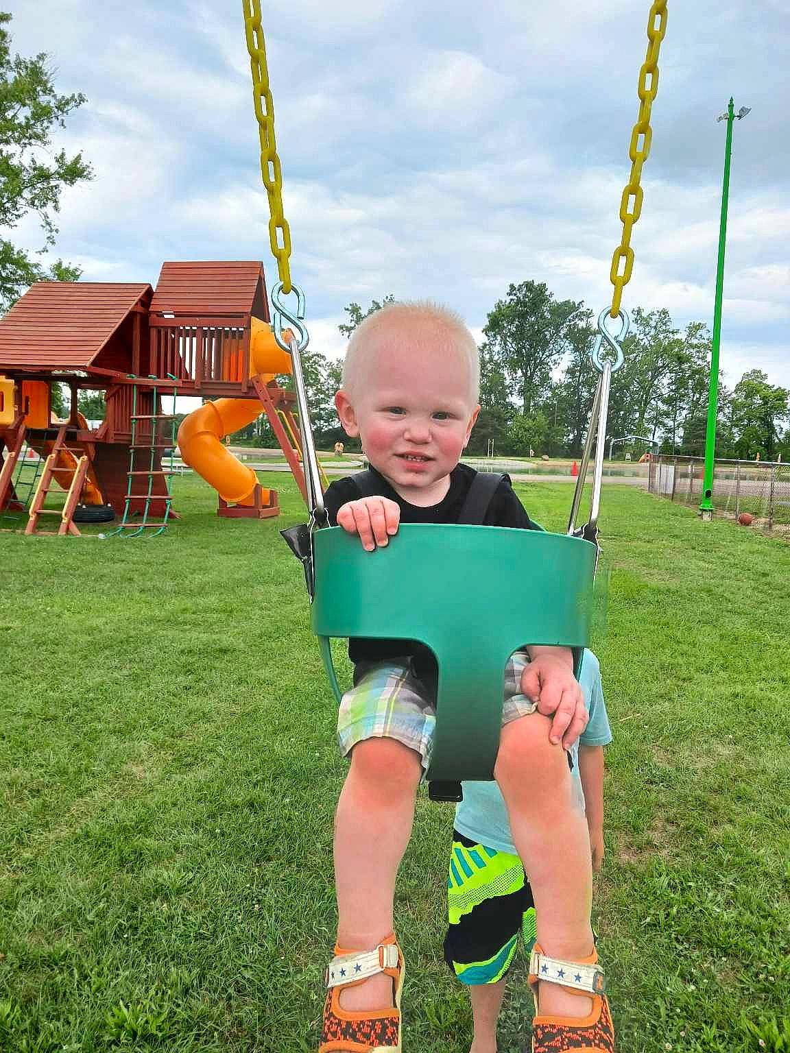 Dawson joined the competition — help win amazing prizes! baby, child, city, cloud, fun, grass, happy, human_settlement, joy, lawn, leisure, outdoor_play_equipment, people_in_nature, person, playground, recreation, shorts, sky, smile, swing