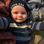 Stellar joined the competition — help win amazing prizes! baby, child, infant, hat, clothing, striped_sweater, blanket, cozy, smile, face, person, indoor, cute, young, headwear, reaching_out, soft_texture, warm, happy, portrait