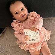Thalya participe au concours pour gagner de l'argent avec cette photo : baby, card, child, closeup, couch, cute, fabric, happy, holding_object, indoor, infant, lace, person, pillow, pink_dress, portrait, sitting, six_months, smiling, young_child