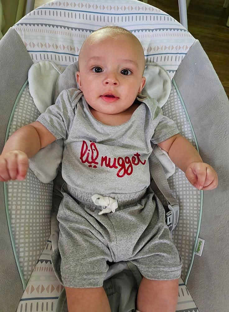 Oakland joined the competition — help win amazing prizes! baby, infant, child, gray_clothing, baby_rocker, patterned_cushion, cute, seated, indoors, wide_eyes, curious, comfortable, smiling, head, arms, legs, casual, young, portrait, human