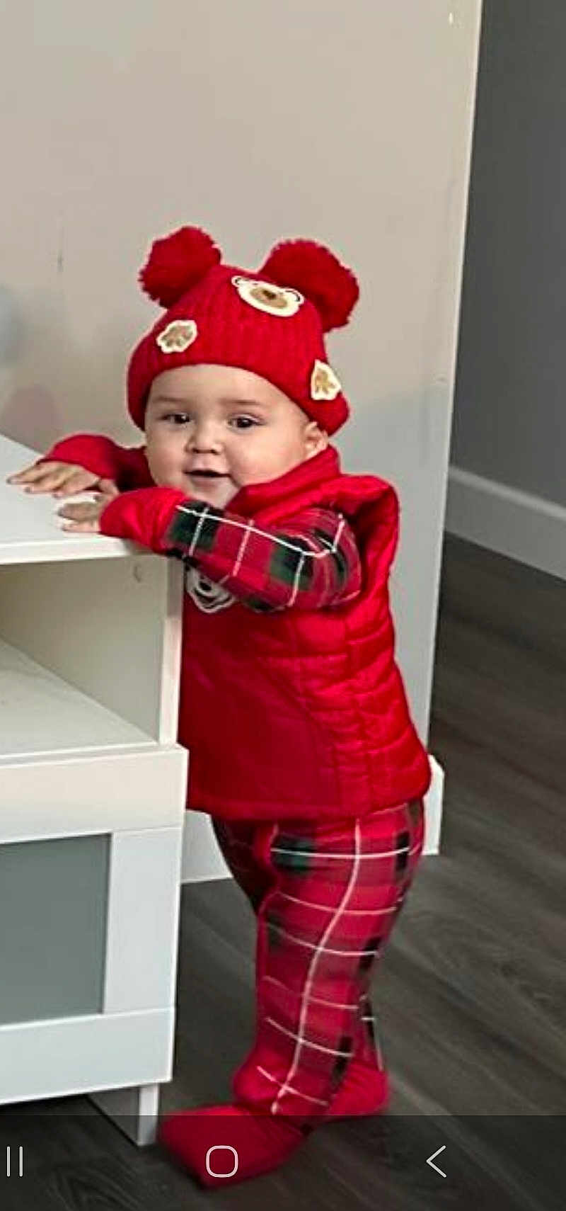 Thiago joined the competition — help win amazing prizes! toddler, child, red_hat, pajamas, red_vest, plaid, indoor, wood_floor, furniture, standing, cute, baby, smiling, winter_clothing, hat_with_pom_poms, home, person, young_child, playful, cozy
