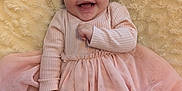 Callie is registered to the contest to win money with this photo: baby, blanket, cheerful, child, closeup, cozy, cute, fuzzy, happy, indoors, infant, long_sleeve, lying_down, pink_dress, portrait, small_hand, smile, soft_texture, tulle, warm_colors