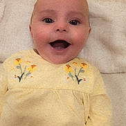 Callie joined the competition — help win amazing prizes! baby, blanket, child, cute, embroidery, eyes, face, flower_design, hand, happy, head, indoors, infant, lying_down, mouth, portrait, skin, smiling, yellow_clothing, young