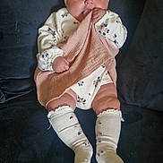 Ayra is registered to the contest to win money with this photo: baby, blanket, child, clothing, couch, cute, face, floral, footwear, hand, headband, indoors, infant, leg, person, pink, sitting, sock, soft, white