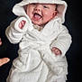 Ayra is registered to the contest to win money with this photo: baby, child, smiling, white_robe, hood, infant, happy, cute, clothing, sitting, indoor, soft_texture, portrait, person, hand, face, legs, sock, warm, cozy