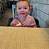 baby, child, infant, restaurant, high_chair, bottle, smiling, happy, face, portrait, sitting, indoor, table, tile_wall, menu_board, cafe, dining, pink_shirt, hand, photography