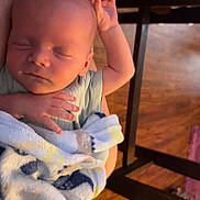 Wyatt joined the competition — help win amazing prizes! baby, newborn, sleeping, blanket, arms, person, indoor, wooden_floor, chair, hand, peaceful, cozy, infant, soft, bedroom, comfort, rest, child, portrait, relaxation