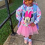 child, girl, smiling, sidewalk, pink_tutu, minnie_mouse, sweatshirt, backpack, beads, hair_bow, shoes, outdoor, railing, grass, concrete, casual_clothing, happy, posing, fashion, cute