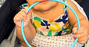 Sariyah is registered to the contest to win money with this photo: adorable, baby, blue_ring, chewing, child, closeup, colorful_clothing, cute, expression, face, feet, hands, indoors, infant, patterned_clothes, playful, sitting, stroller, toy, young_child