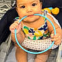 Sariyah is registered to the contest to win money with this photo: baby, child, infant, stroller, blue_ring, colorful_clothing, chewing, cute, sitting, hands, feet, indoors, playful, face, expression, young_child, toy, patterned_clothes, closeup, adorable