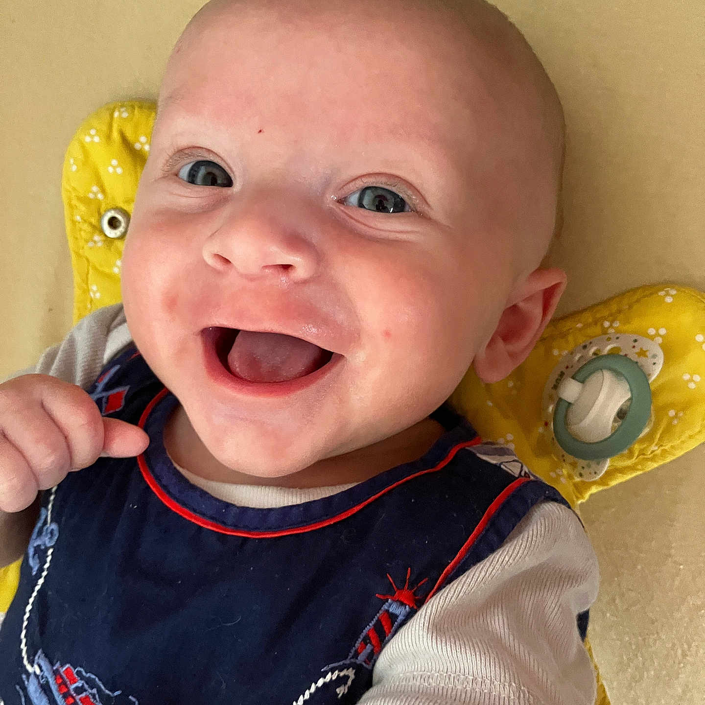 Lucas a rejoint le concours — aidez-le/la à gagner de superbes lots ! baby, blue_eyes, child, clothing, cute, expression, face, hand, happy, indoors, infant, lying_down, mouth_open, navy_blue, pacifier, portrait, short_sleeves, skin, smiling, yellow_cushion