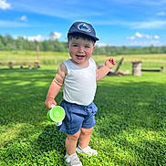 Brooks is registered to the contest to win money with this photo: baby, baseballcap, cap, clothing, face, field, grass, green, hat, head, nature, outdoors, pants, park, person, photography, plant, portrait, shorts, summer