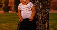 Armonii is registered to the contest to win money with this photo: baby, child, smiling, tree, outdoor, grass, sunset, pants, red_shoes, white_shirt, happy, portrait, nature, person, young_child, casual_clothing, standing, daylight, background_blur, cute