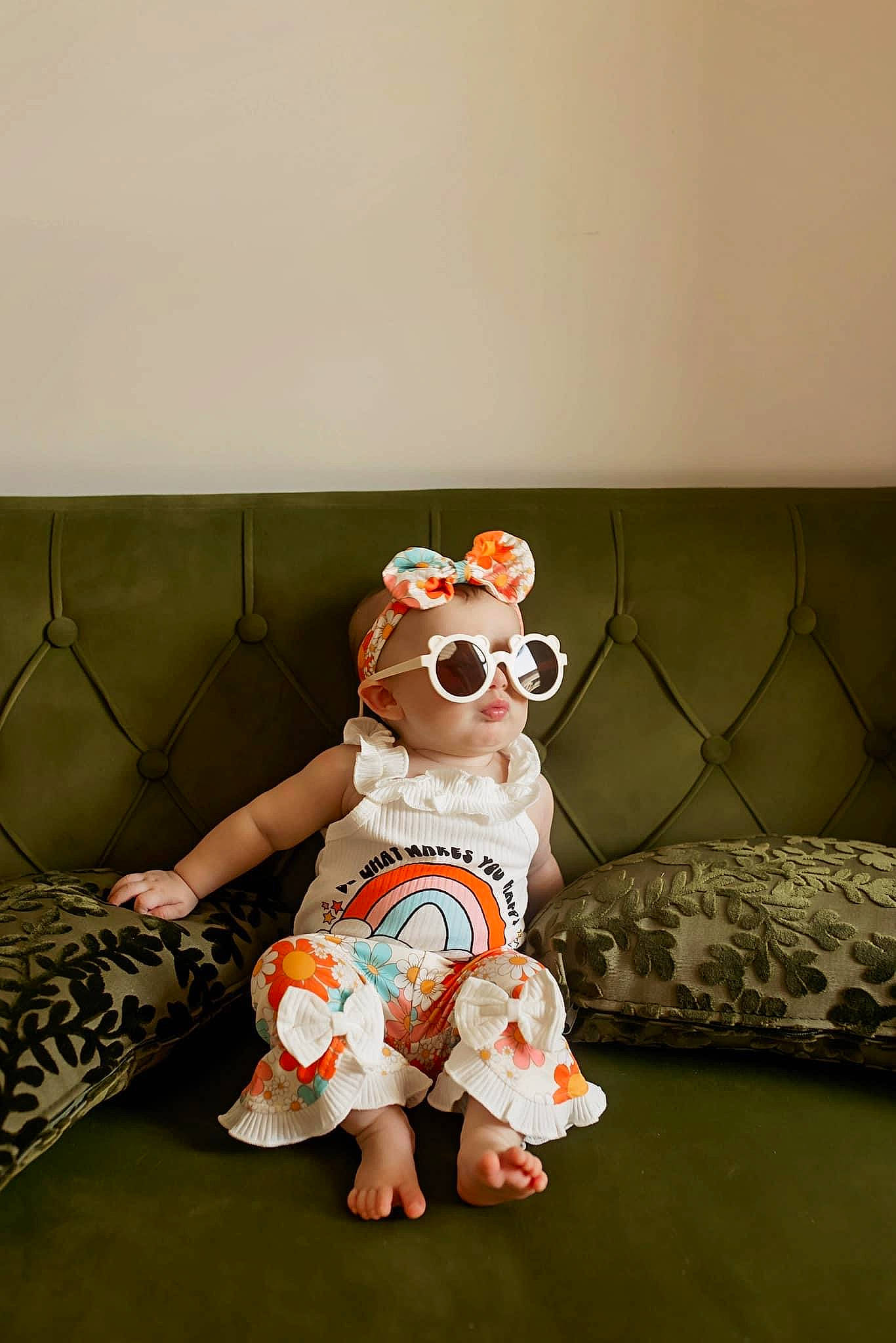 Hadley is registered to the contest to win money with this photo: baby, baby_toddler_clothing, barefoot, child, couch, event, fawn, flooring, foot, fur, happy, linens, pattern, peach, person, room, sitting, stuffed_toy, teddy_bear, toy