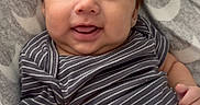 Jacob is registered to the contest to win money with this photo: baby, blanket, child, cozy, cute, expression, face, hair, happy, indoors, infant, lying_down, patterned_blanket, portrait, skin, smiling, soft_toys, striped_clothing, thumbs_up, young