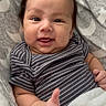 Jacob is registered to the contest to win money with this photo: baby, infant, smiling, thumbs_up, blanket, striped_clothing, cute, happy, face, hair, child, lying_down, soft_toys, patterned_blanket, indoors, portrait, skin, expression, young, cozy