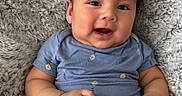 Jacob is registered to the contest to win money with this photo: baby, infant, smiling, blue_onesie, hand_holding, blanket, fluffy, cute, face, portrait, happy, skin, person, child, baby_clothes, newborn, lying_down, fingers, close_up, soft_texture