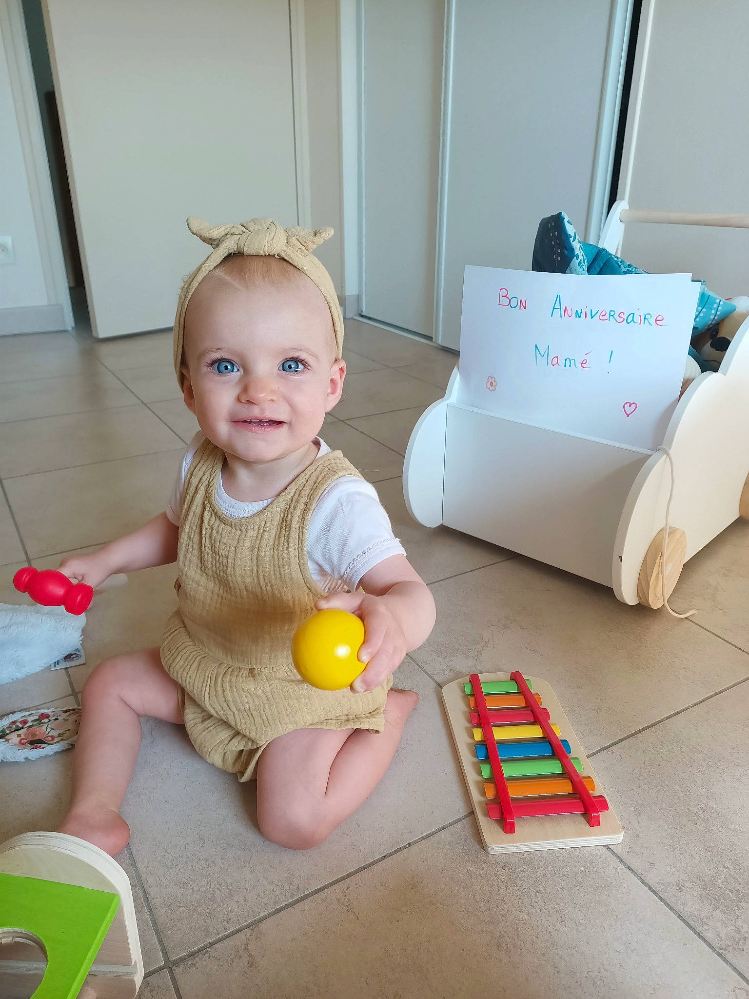 Julia a rejoint le concours — aidez-le/la à gagner de superbes lots ! baby, baby_playing_with_toys, baby_products, baby_toddler_clothing, baby_toys, box, child, floor, flooring, fun, hardwood, joy, paper_product, person, play, room, sitting, smile, toddler, toy