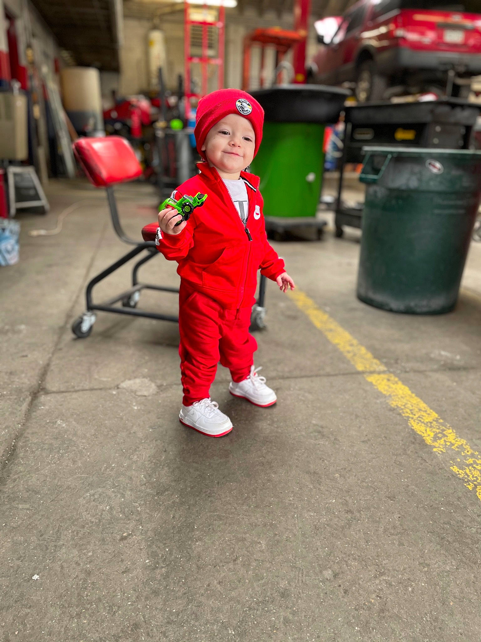 Sebastian is registered to the contest to win money with this photo: asphalt, chair, child, city, cleanliness, event, flooring, fun, headwear, joy, leisure, person, plant, road, road_surface, sidewalk, smile, sneakers, standing, toddler