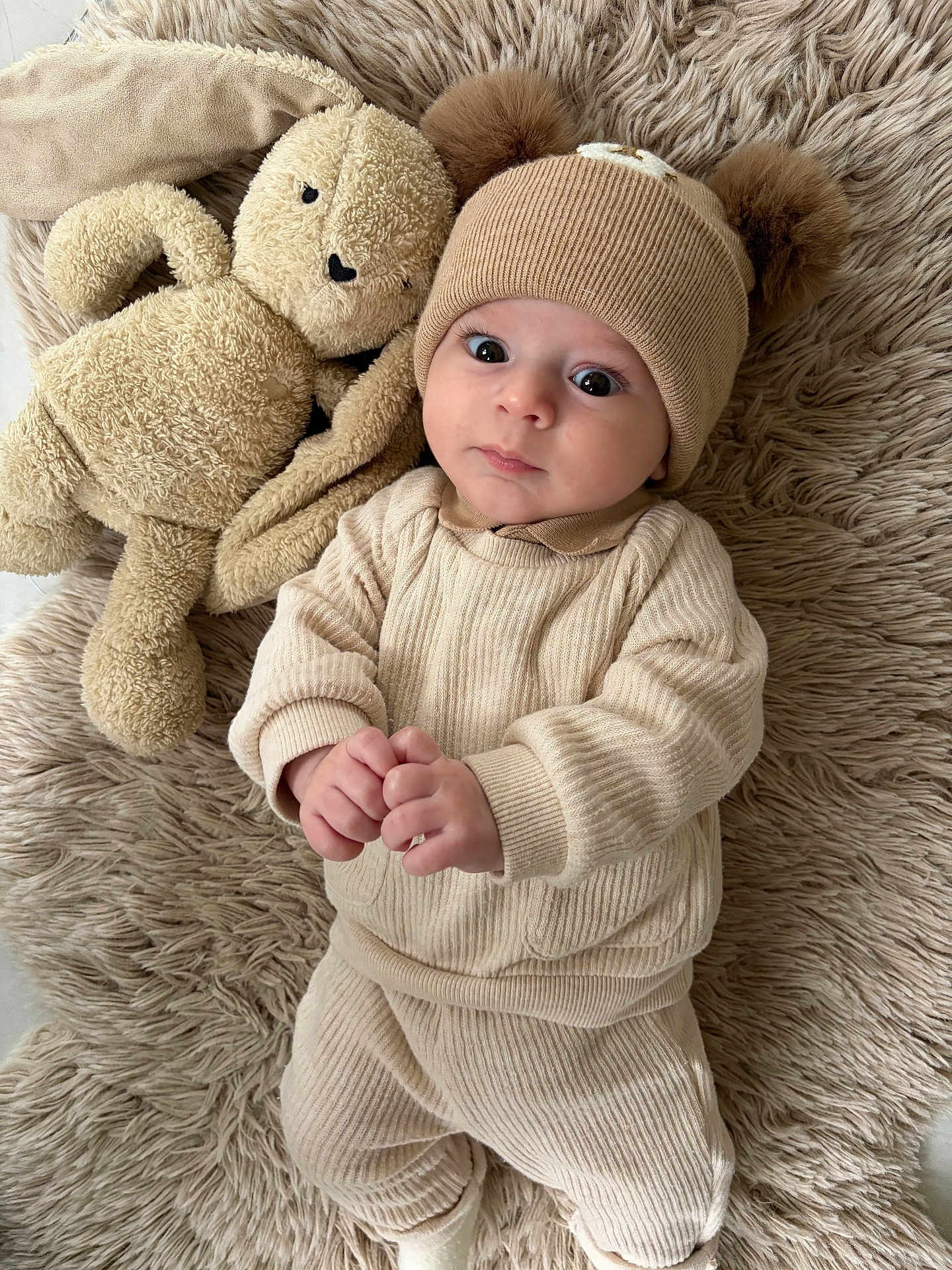 Harry participe au concours pour gagner de l'argent avec cette photo : baby, infant, hat, knitwear, beige, stuffed_animal, bunny, plush_toy, rug, soft_texture, cute, child, indoor, clothing, portrait, lying_down, hands, expression, cozy, adorable