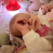 Alice a rejoint le concours — aidez-le/la à gagner de superbes lots ! baby, sleeping, pacifier, plush_toy, blanket, soft_lighting, night_light, close_up, infant, cozy, bedtime, pink, cute, peaceful, hand, face, indoors, child, rest, comfort