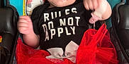 Zaria is registered to the contest to win money with this photo: baby, car_seat, tutu, smiling, clothing, booties, infant, patterned, cute, happy, indoor, child, person, fabric, text_on_clothing, red, black, white, floral, seat