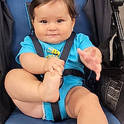 John is registered to the contest to win money with this photo: baby, child, stroller, blue_clothing, infant, cute, smiling, chubby, playful, seatbelt, indoor, person, foot, hand, young_child, baby_boy, casual, portrait, seat, happy