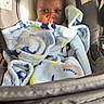 Tremeire is registered to the contest to win money with this photo: baby, child, blanket, car_seat, seat, infant, face, expression, warning_label, sunlight, indoor, clothing, wrapped, sitting, head, person, young_child, portrait, cozy, warm