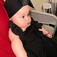Luciana Vargas is registered to the contest to win money with this photo: baby, infant, black_clothing, headband, chubby_cheeks, curious_look, red_fabric, folding_chair, indoor, portrait, cute, child, person, sitting, arm, skin, young, headwear, closeup, fashion