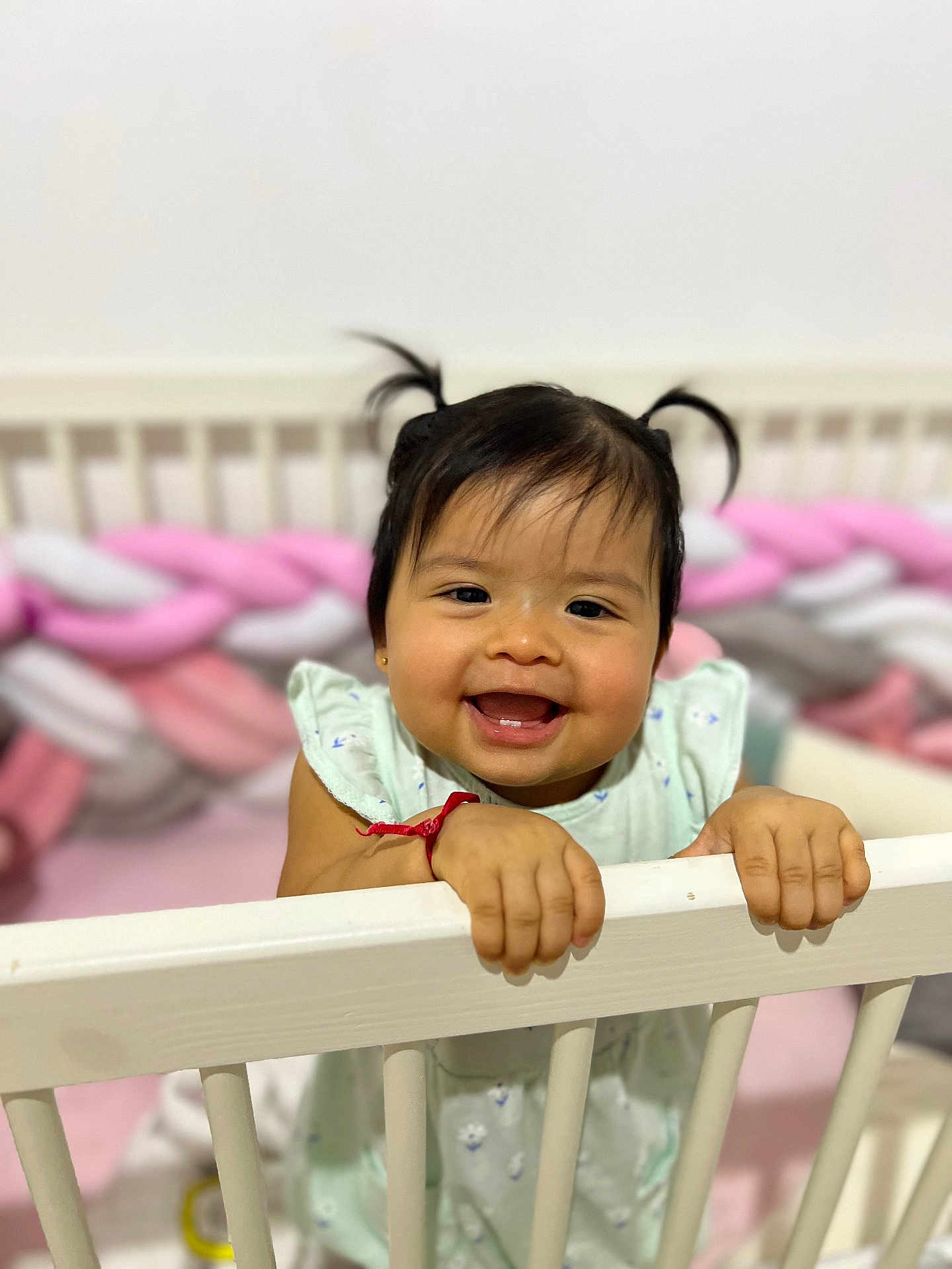 Yumi participe au concours pour gagner de l'argent avec cette photo : baby, child, smiling, crib, pigtails, infant, happy, indoor, toy, braided_bumper, white, cute, face, person, hand, clothing, playful, room, portrait, toddler