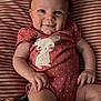 Holloni is registered to the contest to win money with this photo: baby, infant, smile, onesie, polka_dot, cat_design, striped_pillow, hair_tuft, cheeky, cute, child, portrait, indoors, relaxed, person, skin, hand, face, lying_down, happy