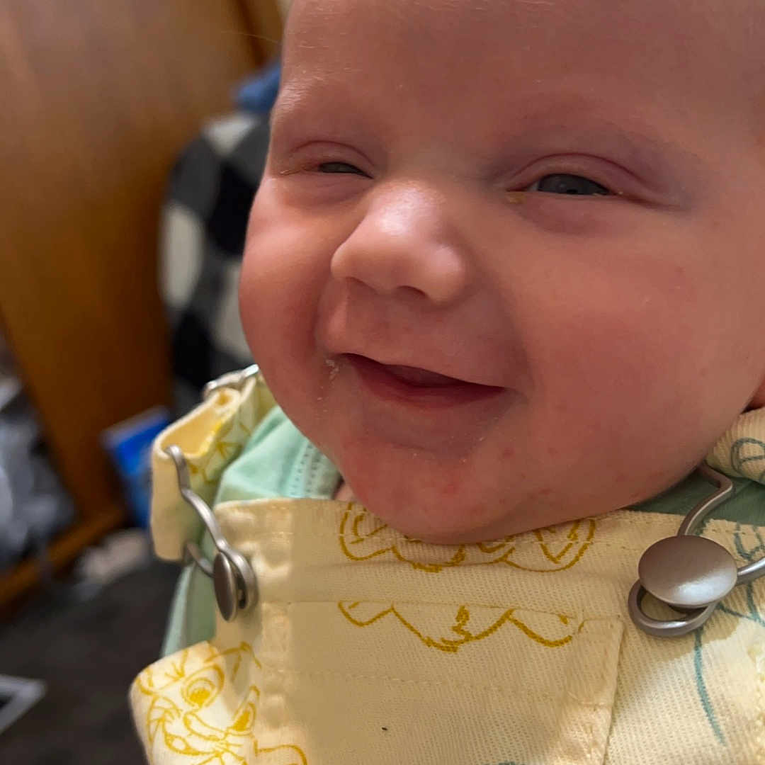 Killian is registered to the contest to win money with this photo: accessories, baby, clothing, coat, cutlery, dress, earring, face, happy, head, jacket, jewelry, laughing, necklace, newborn, person, photography, portrait, smile, spoon