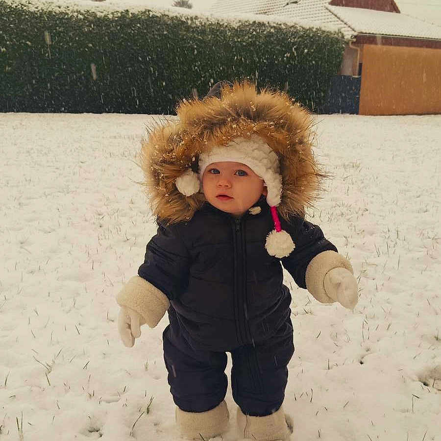 Léonnah participe au concours pour gagner de l'argent avec cette photo : baby, boots, child, cold_weather, curious, daylight, footprints, fur_hood, grass, hat, hedge, house, mittens, outdoor, portrait, snow, snowfall, snowy_ground, standing, winter_clothing