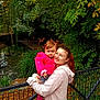 Léonnah a rejoint le concours — aidez-le/la à gagner de superbes lots ! baby, child, woman, person, smile, outdoor, nature, trees, leaves, fence, pond, flamingo, autumn, jacket, hoodie, grass, park, water, happy, holding