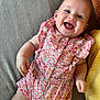 Alina participe au concours pour gagner de l'argent avec cette photo : baby, infant, smiling, happy, romper, floral_pattern, clothing, cute, child, person, lying_down, indoors, soft_surface, pillow, skin, face, eyes, hand, leg, casual