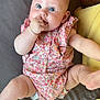 baby, infant, child, blue_eyes, romper, floral_pattern, hand, fist, legs, kicking, bed, pillow, cushion, skin, cute, playful, lying_down, indoors, closeup, person