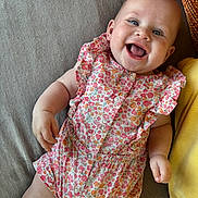 Alina participe au concours pour gagner de l'argent avec cette photo : baby, smiling, infant, floral_clothing, romper, couch, pillow, happy, lying_down, indoors, cute, child, person, skin, face, cheerful, baby_girl, cozy, comfort, bright_eyes