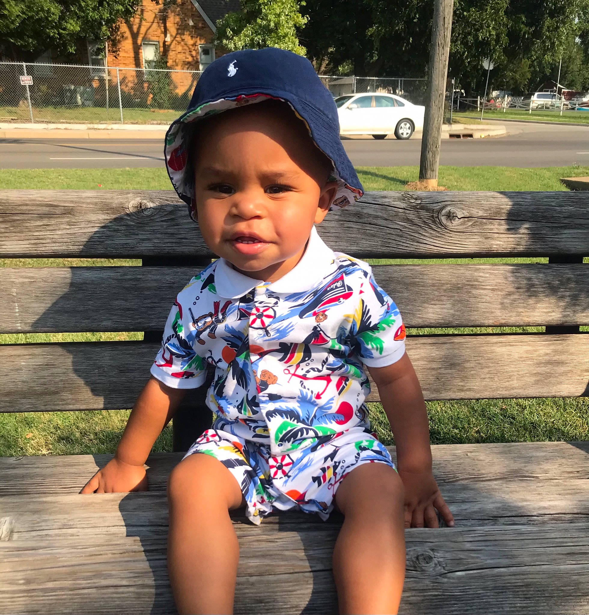Rah is registered to the contest to win money with this photo: baby_toddler_clothing, baseball_cap, cap, cool, facial_expression, fun, grass, happy, headwear, leaf, leisure, mammal, morning, person, plant, public_space, sleeve, standing, sunlight, t_shirt