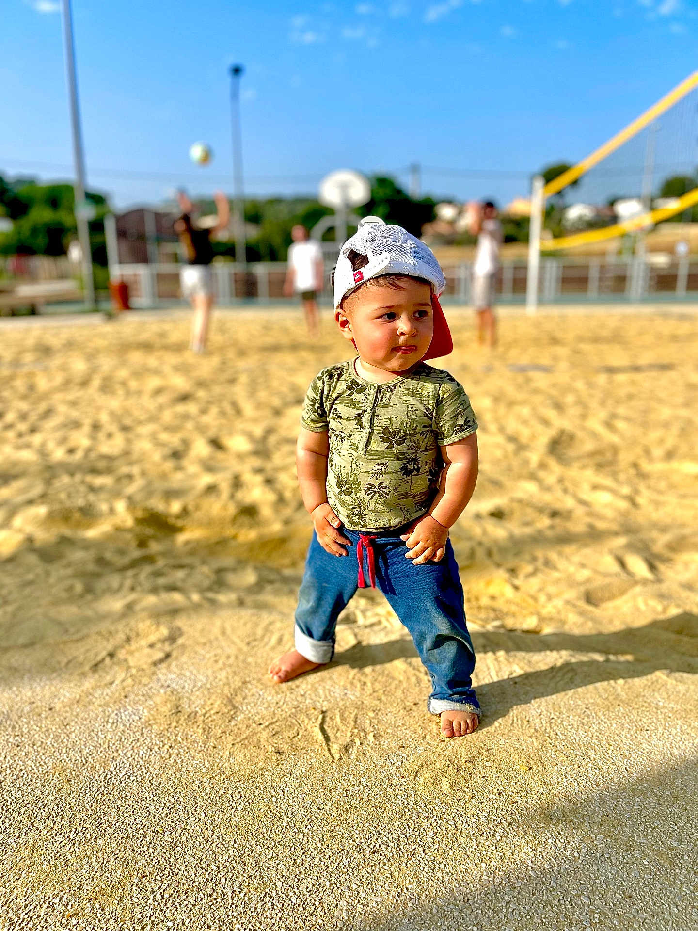Lenny participe au concours pour gagner de l'argent avec cette photo : toddler, child, sand, volleyball_court, hat, baseball_cap, barefoot, jeans, tshirt, outdoor, sunny, playing, sports, volleyball, people, blurred_background, summer, recreation, fun, casual_clothing