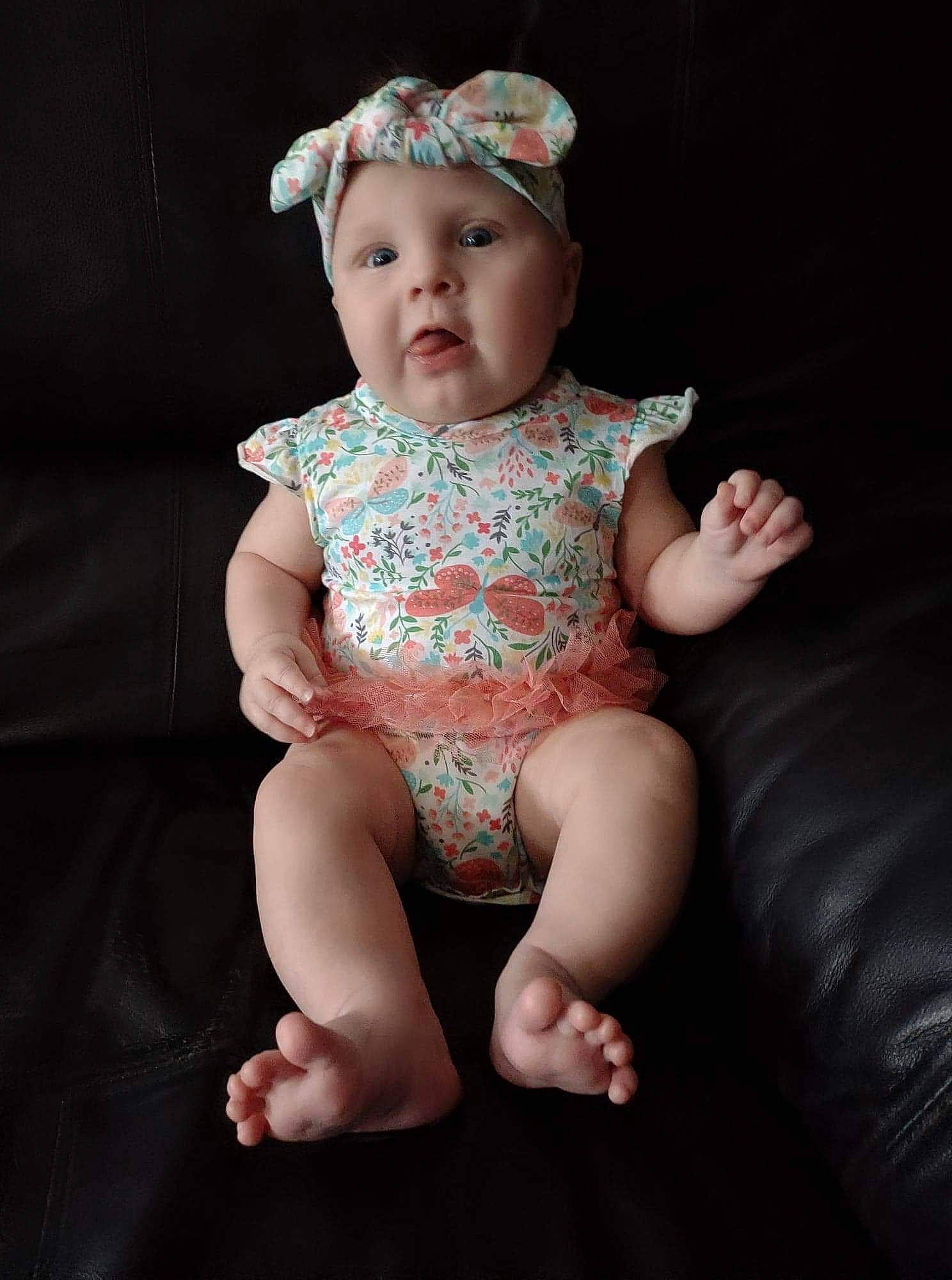 Gabrielle is registered to the contest to win money with this photo: baby, baby_toddler_clothing, barefoot, cheek, eye, finger, flash_photography, foot, head, headgear, headwear, human_body, human_leg, iris, knee, neck, person, pink, skin, sleeve