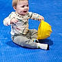 toddler, child, indoor, blue_floor, hard_hat, yellow, dinosaur_print, long_sleeve_shirt, gray_pants, socks, sitting, happy, smiling, playful, young_child, floor_mat, toy, casual_clothing, person, cute