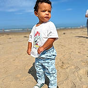 Lemony participe au concours pour gagner de l'argent avec cette photo : beach, casual_clothing, child, confident, curly_hair, daytime, expression, footwear, mickey_mouse, outdoor, pants, person, sand, sky, sneakers, standing, sunny, toddler, tshirt, vacation
