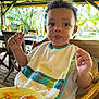 Lemony participe au concours pour gagner de l'argent avec cette photo : bib, carrot, child, curly_hair, daylight, eating, food, fried_food, high_chair, napkin, outdoor, person, plate, portrait, sunlight, table, toddler, tropical, wooden_chair, wooden_floor
