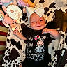 Brinley is registered to the contest to win money with this photo: baby, baby_girl, blanket, bow, child, clothing, cow_print, crib, cute, happy, headband, indoors, infant, lying_down, onesie, plush_toys, portrait, smiling, soft_toys, stuffed_animals