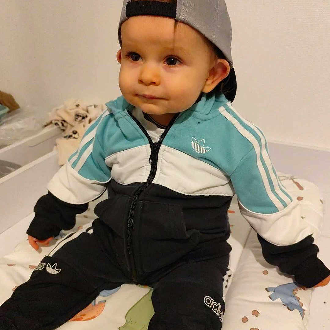 Ayden participe au concours pour gagner de l'argent avec cette photo : baseballcap, bed, boy, cap, child, clothing, coat, crib, face, furniture, hat, head, hosiery, jacket, male, pants, person, photography, portrait, sock