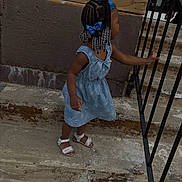 Leilani joined the competition — help win amazing prizes! child, girl, braids, blue_bows, dress, sandals, stairs, railing, concrete, outdoor, curious, side_view, young, person, hair_accessories, footwear, wall, texture, daylight, standing