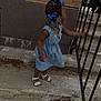child, girl, braids, blue_bows, dress, sandals, stairs, railing, concrete, outdoor, curious, side_view, young, person, hair_accessories, footwear, wall, texture, daylight, standing