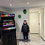 Mathis participe au concours pour gagner de l'argent avec cette photo : arcade_machine, black_jacket, boy, casual_clothing, child, door, entertainment, floor_tiles, gaming, hulk, indoor, lighting, modern_room, portrait, smiling, sneakers, standing, technology, wall_art, young