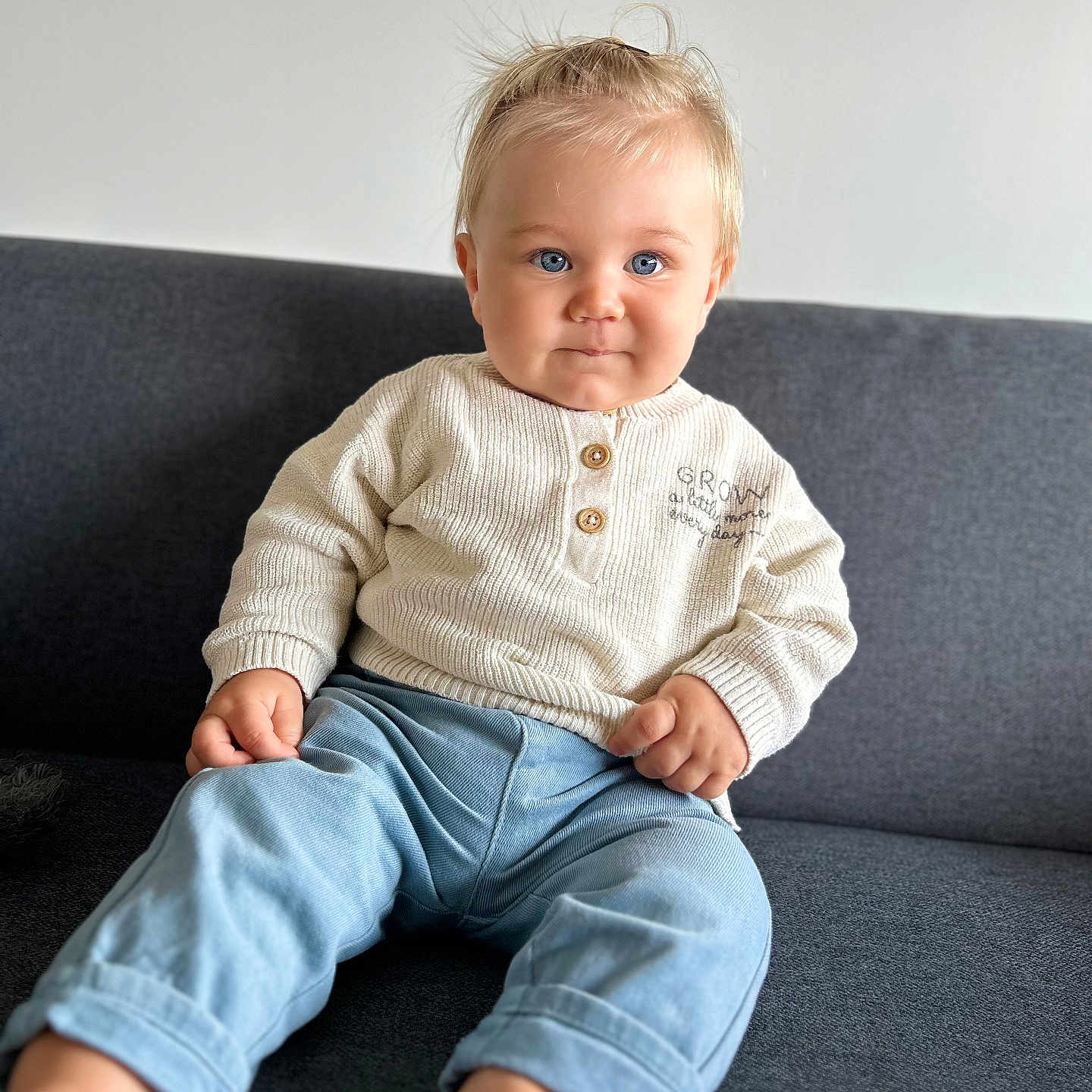 Milan a rejoint le concours — aidez-le/la à gagner de superbes lots ! baby, barefoot, blond_hair, blue_eyes, casual_clothing, child, couch, cute, furniture, home, indoor, infant, light, pants, person, portrait, relaxed, sitting, smiling, sweater