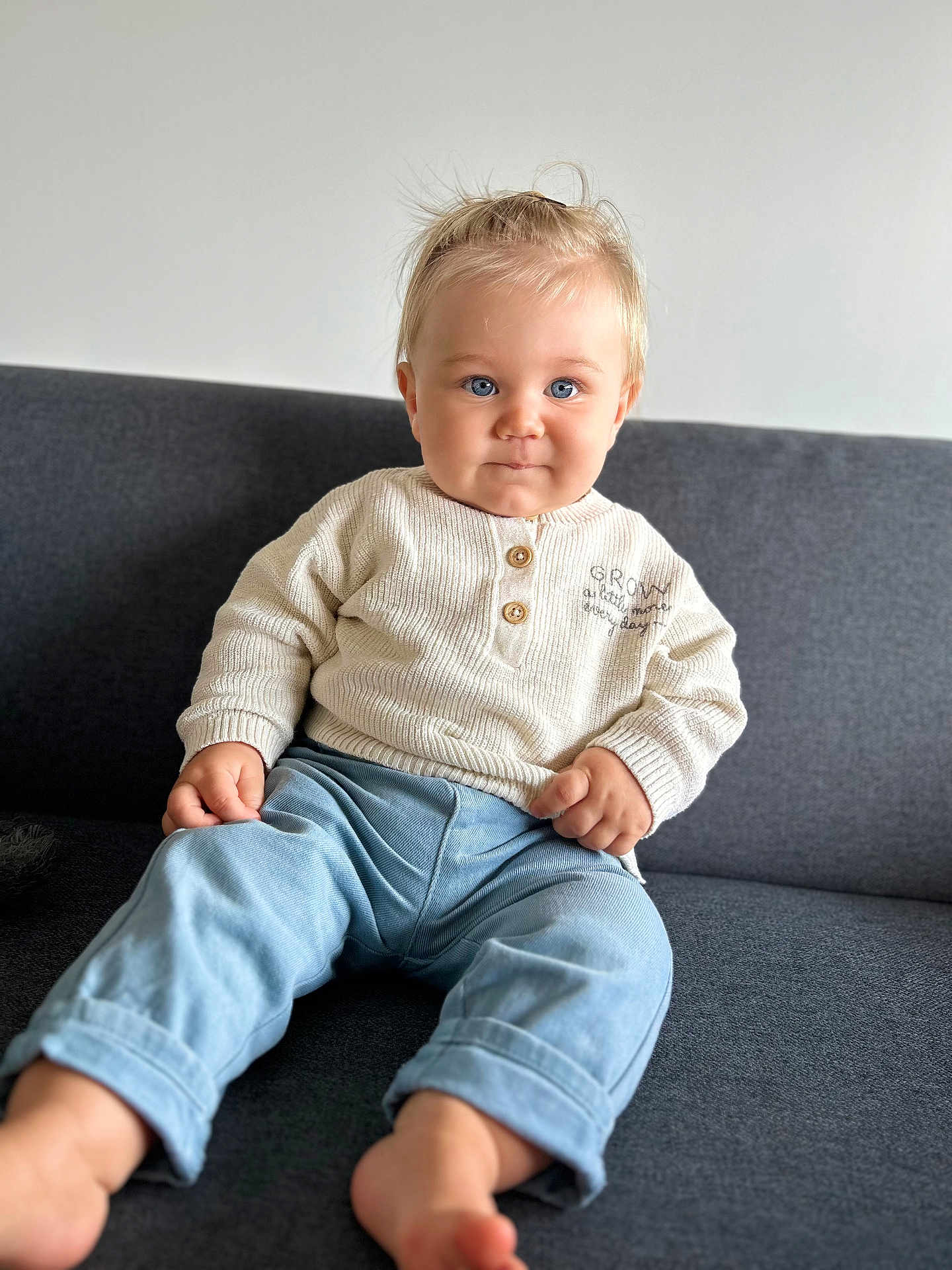 Milan a rejoint le concours — aidez-le/la à gagner de superbes lots ! baby, child, sitting, indoor, couch, blue_eyes, sweater, pants, barefoot, blond_hair, portrait, cute, infant, casual_clothing, home, smiling, person, furniture, relaxed, light